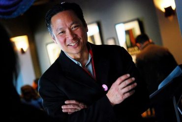 A middle aged Japanese American man is smiling at the camera.