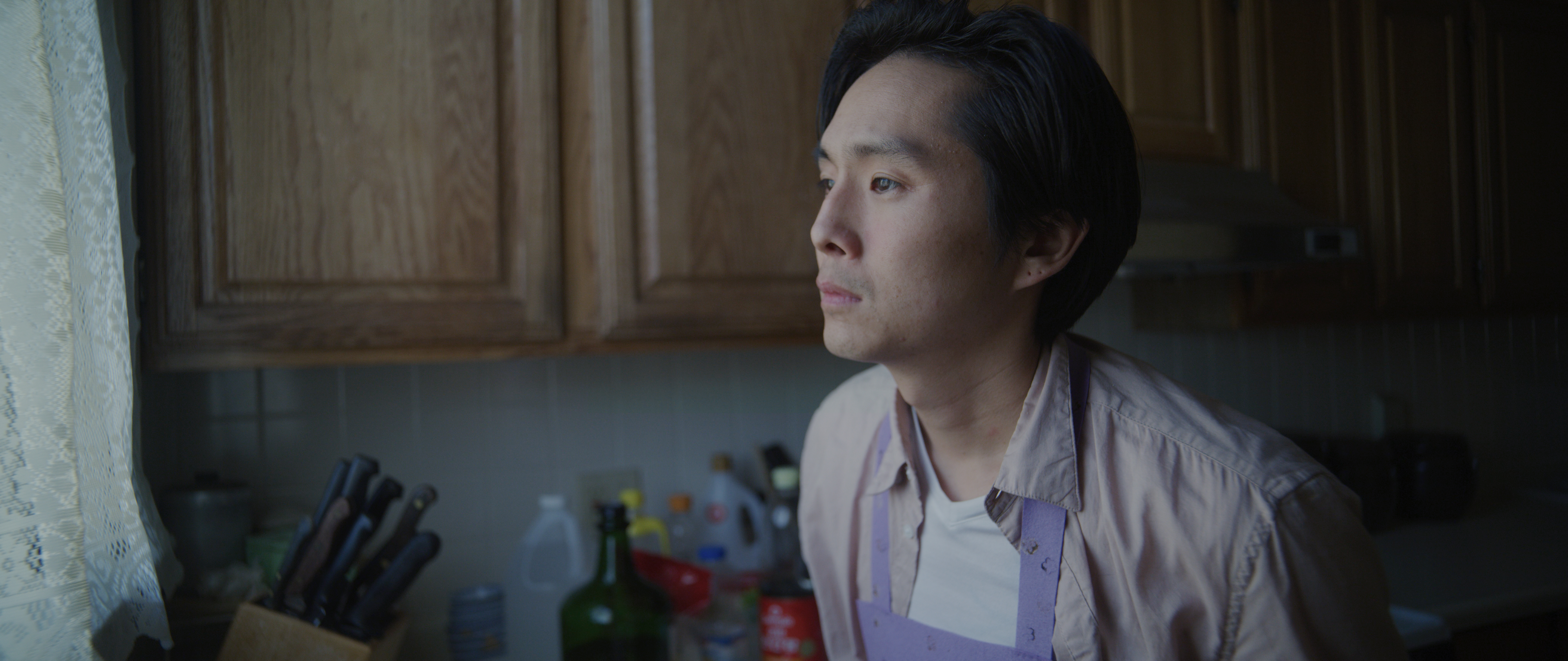 A Korean American man looks off into the distance forlornly.
