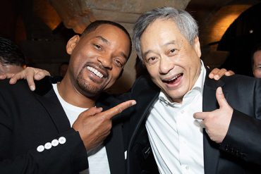 An African American man and Chinese American man smile for the camera while they are hugging.