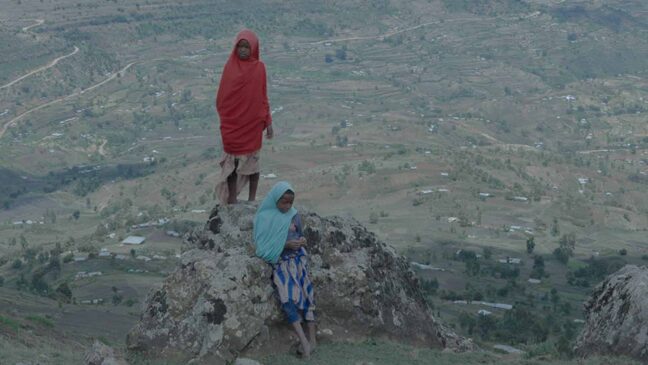 2 people standing on a mountain wearing red and blue