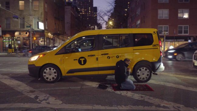 man praying outside his taxi