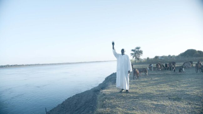 Man wearing white waving from a far by the beach